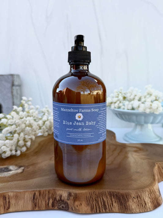 Blue Jean Baby goat milk lotion by Mazzeltov Farms Soap Co. 16 oz bottle with a bright floral spring scent featuring lily, freesia, citrus, and soft musk.