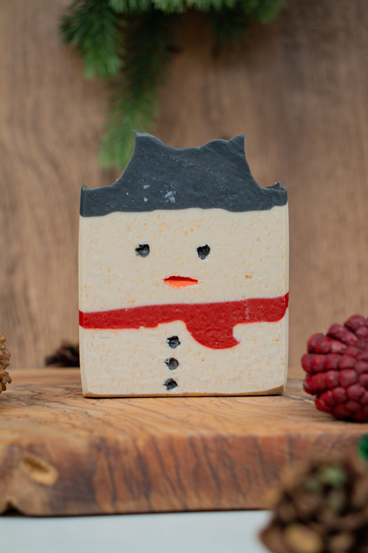 Frosty the Soapman limited edition handmade goat milk soap bar from Mazzeltov Farms Soap Co. Charcoal, cream, and red layered design with a fresh winter forest scent.