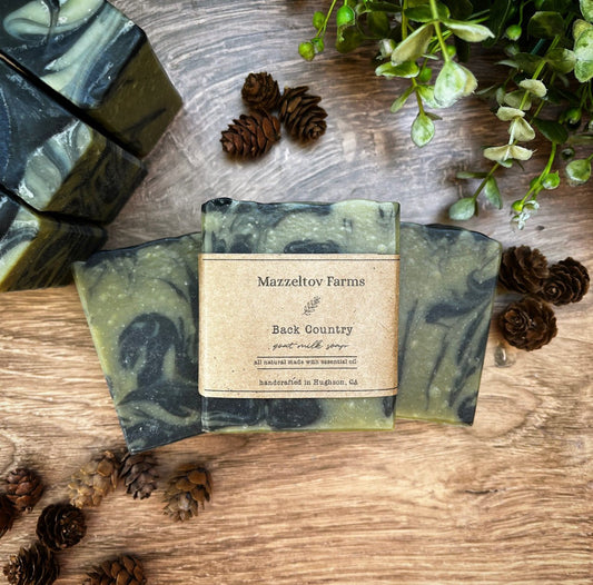 Back Country goat milk soap bar handmade by Mazzeltov Farms Soap Co. Green and black bar naturally colored with spinach powder and activated charcoal, scented with juniper berry, fir needle, patchouli, and peppermint.